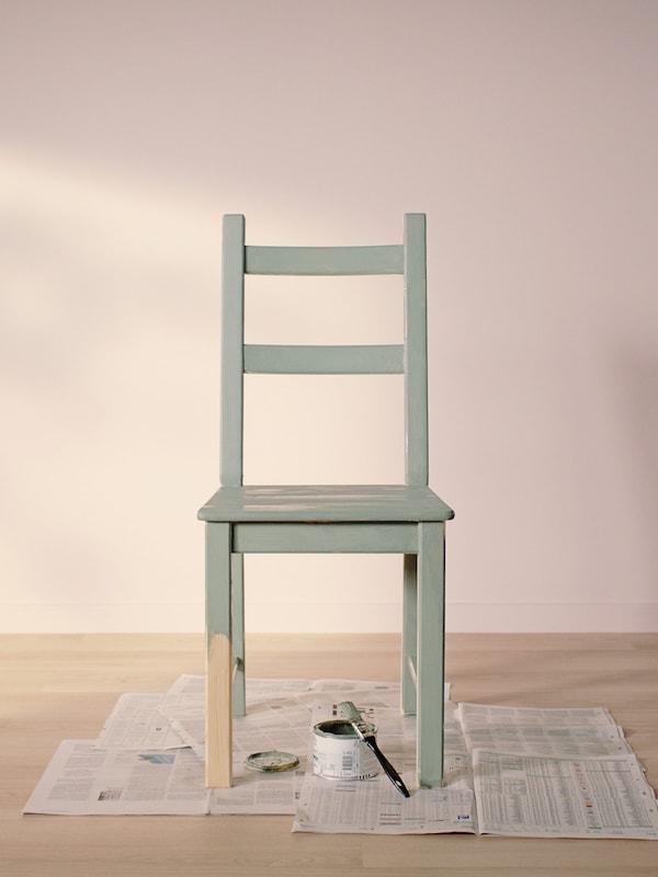 IVAR椅子涂浅绿色站在旧报纸在一个空房间木地板光和亮粉红色的墙壁。