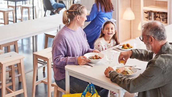 Kobieta, mzyzyzna i dziewczynka siedzagicy przy steal w Restauracji亚博平台信誉怎么样 IKEA i jedzagicy obiad。
