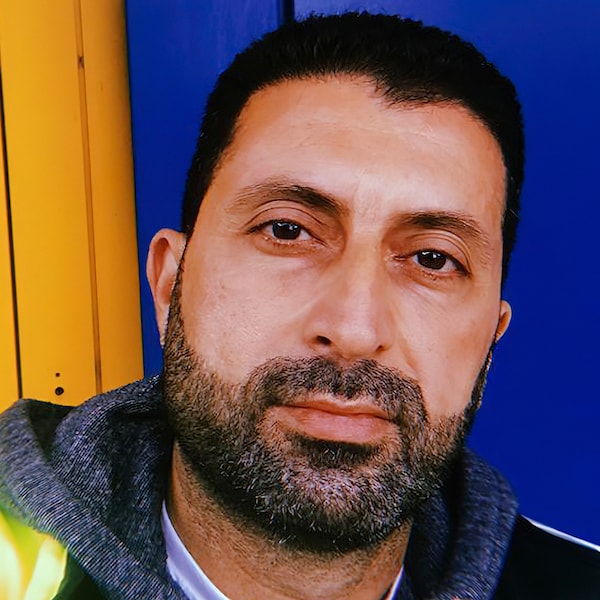 Odal,现在从伊拉克难民为宜家瑞士工作,站在蓝色和黄色的背景下。亚博平台信誉怎么样