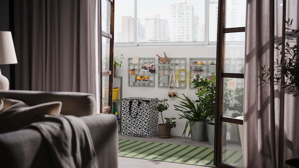 开门到阳台与灰绿色的SNICKRA存储板在墙上,黑色/白色袋子,大盆栽和地毯。
