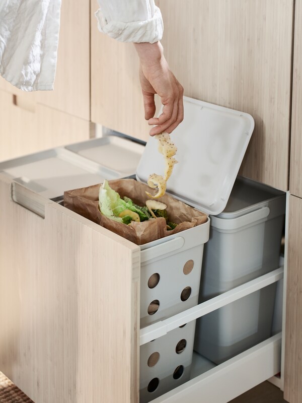 Osoba pozbywa siędomowych odpadow咱pomocąsegregacji resztek jedzenia pojemnika做segregacji odpadow HALLBAR znajdującego sięw szufladzie z czterema pojemnikami。