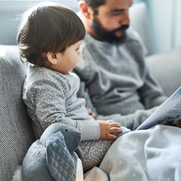 PEKHULT毛绒玩具了夜灯和LEN毯子旁边一个小男孩和他的父亲阅读米色/棕色的沙发。
