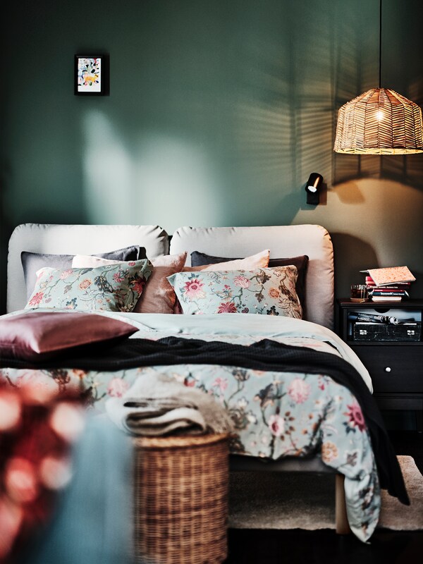罗摩łożka tapicerowanego SAGESUND poduszki w rożowo-szarych poszewkach SANELA oraz pościel NASSELKLOCKA w kwiatowe wzory。