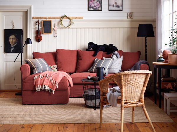 Rotes GRÖNLID在hellen Wohnzimmer的einem里的Sofa auf einem beigefarbenen Teppich。