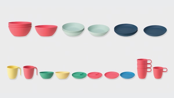 几只五颜六色的碗、盘子和杯子在灰色的背景下排成一排。