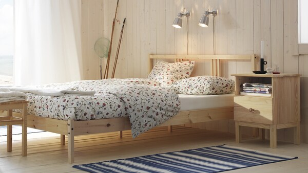 简单、简约的卧室与TARVA床架松木制成,并且木旁边的床头柜上。窗户框架与一个纯粹的窗帘,让阳光流进房间。
