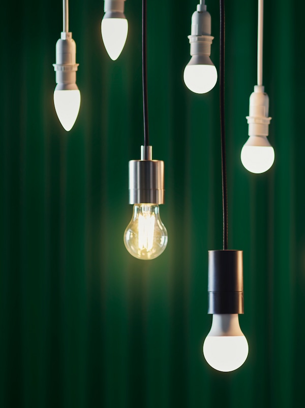 6各设计LED灯泡挂在不同的高度在一个黑暗的背景下绿色的窗帘。