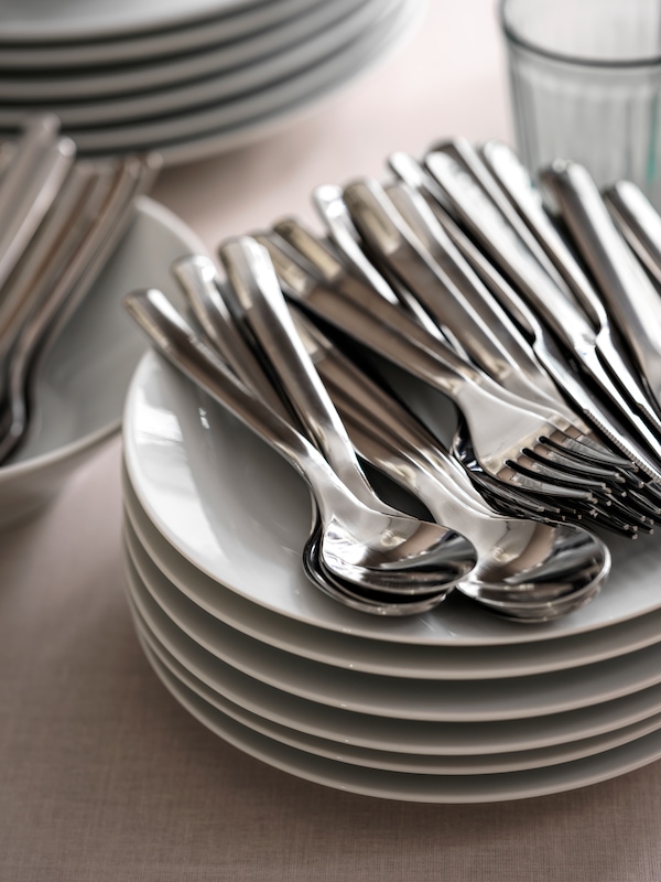 成堆的盘子,眼镜,宜家365 +餐具和其他餐具桌面米色亚博平台信誉怎么样桌布。