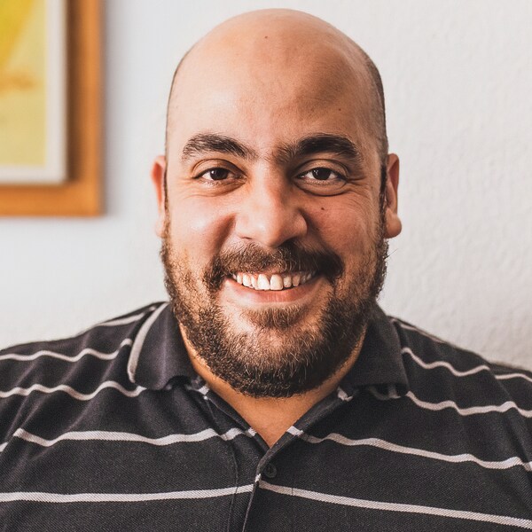 Tarek, syrisk flygtning og medarbejder我宜家Spa亚博平台信誉怎么样nien,微笑者iført en布朗——og hvidstribet skjorte。