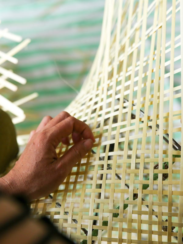 的手工匠,编织一个光,黄色竹子手工晶格金属灯头上。