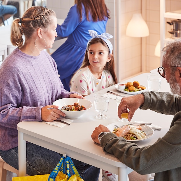 两个成人和一个孩子一起享受一顿饭坐在白色的表在瑞典宜家的餐厅。亚博平台信誉怎么样