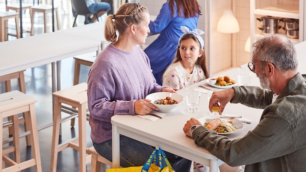 两个成人和一个孩子一起享受一顿饭坐在白色的表在宜家瑞典小酒馆。亚博平台信誉怎么样