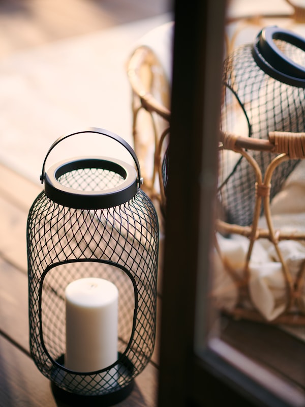 块的两个黑色TOPPIG灯笼蜡烛放在一个木制户外空间一起SNIDAD藤篮。