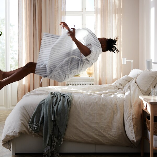 Vo svetlej izbe s roztiahnutými závesmi DYTÅG sa osoba vrhá dozadu na postemalm s 2 zásuvkami。